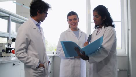 International-Group-of-Scientists-in-Laboratory.science-research,-work-and-people-concept-international-group-of-happy-scientists-with-clipboards-discussing-report-in-laboratory