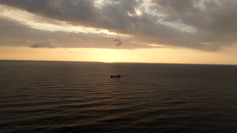 Flying-over-navigating-cargo-ship-with-sunset-in-background