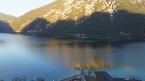 views at sunset of lake achen with calm waters ln tyrol, austria - aerial drone shot