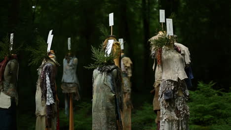 outdoor art installation featuring mannequins dressed in rustic clothing in a forest