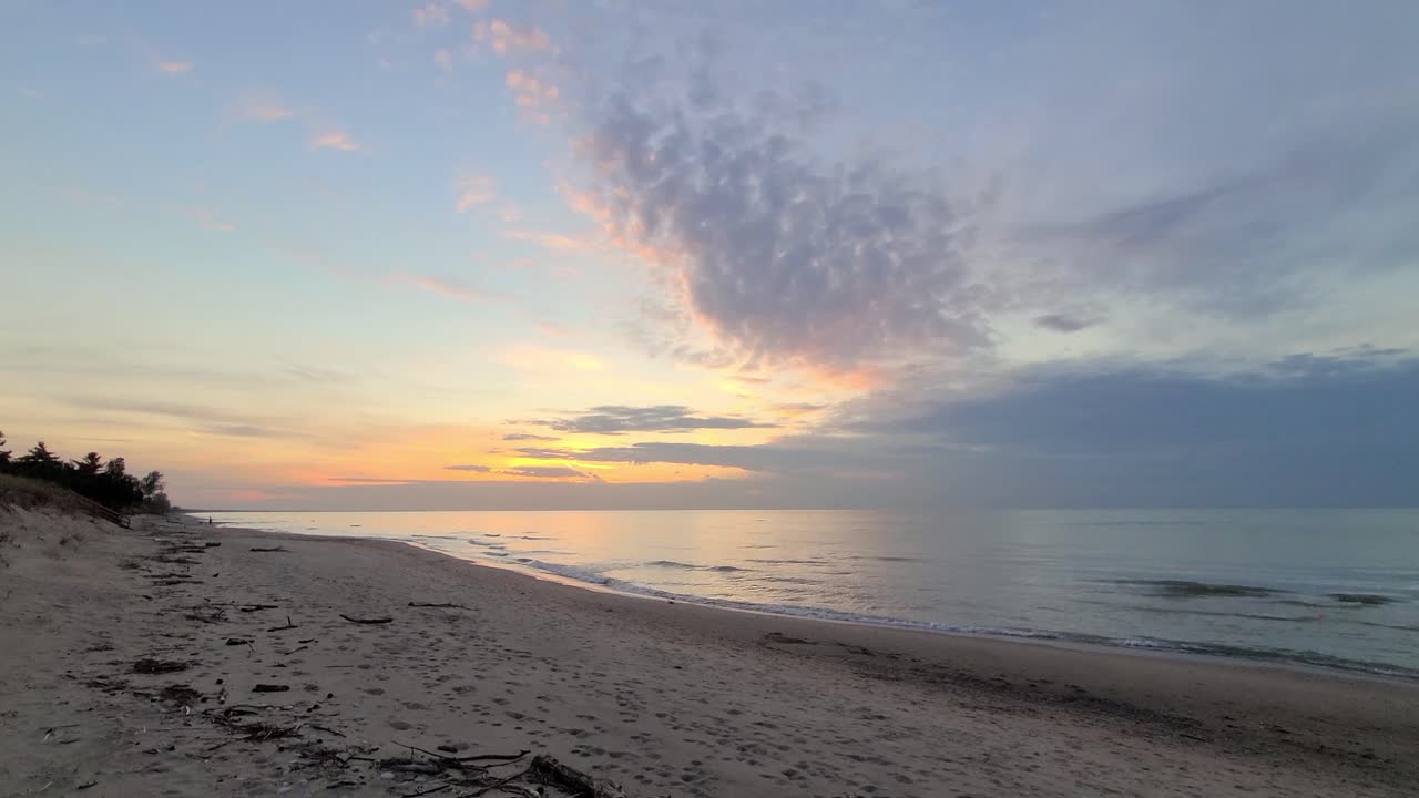 hermosa vista de la puesta de sol detrás de las nubes en una playa de arena, caminando en una playa vacía