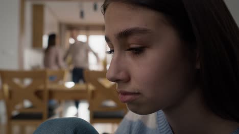 primer plano de una adolescente llorando y padres discutiendo en el fondo