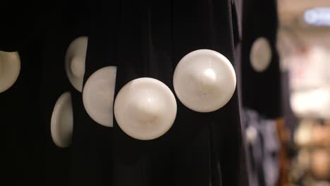 black dress with white buttons on a hanger in a store