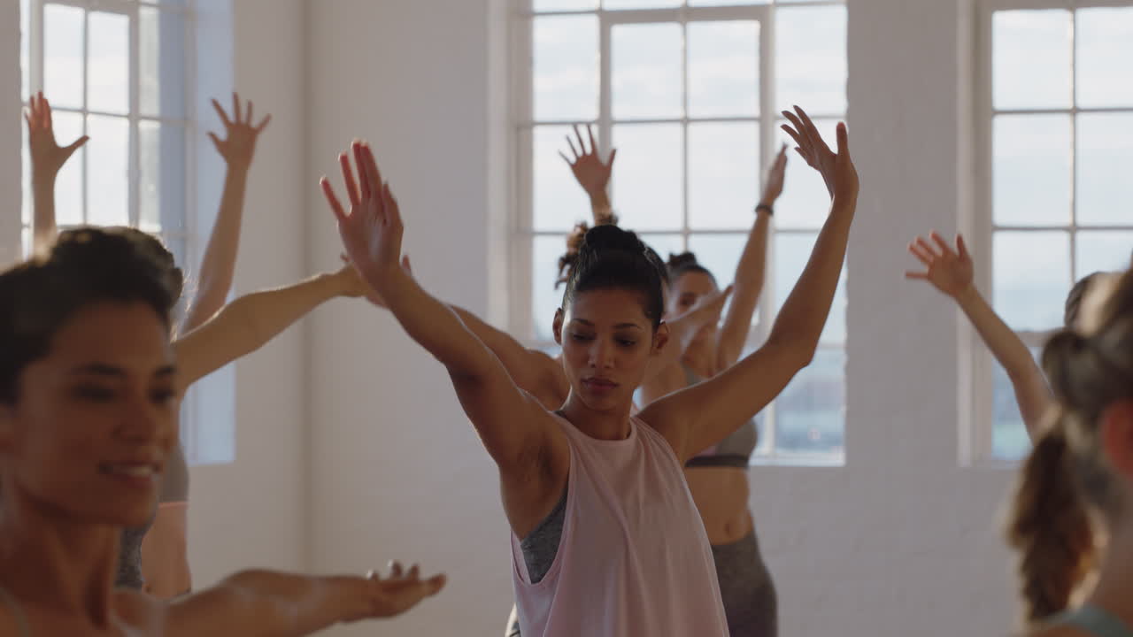 clase de yoga mujer de raza mixta saludable practicando pose guerrera con un grupo de mujeres hermosas disfrutando de un estilo de vida saludable haciendo ejercicio en el gimnasio al amanecer