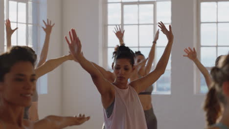 yoga class healthy mixed race woman practicing warrior pose with group of beautiful women enjoying healthy lifestyle exercising in fitness studio training at sunrise