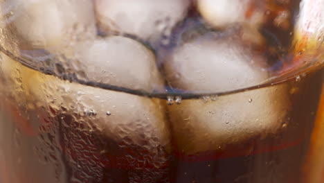 close up, looking through a glass as soda is sipped through a straw