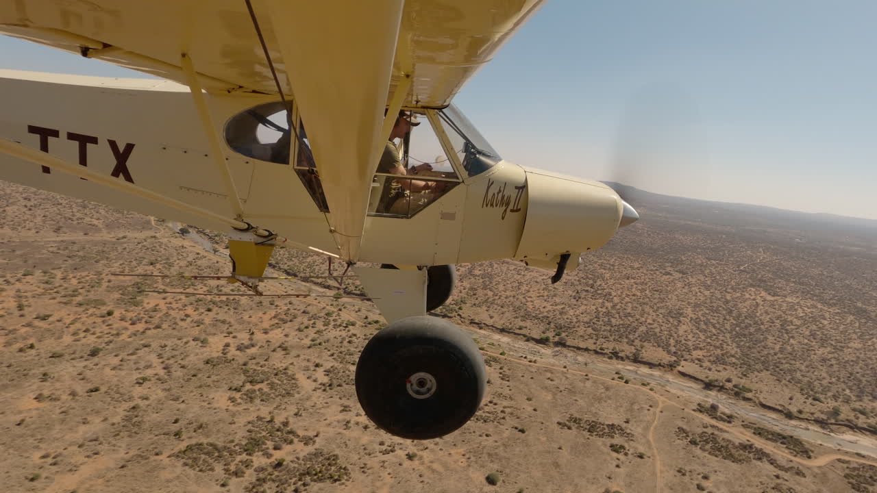 Piccolo aereo leggero sopra il letto di un fiume asciutto in una pianura keniota