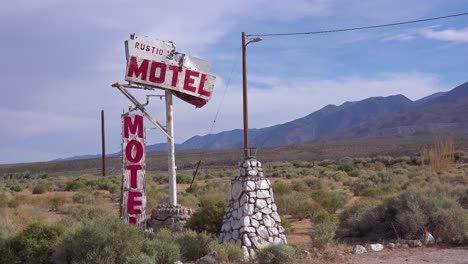 un antiguo cartel de motel rústico abandonado o deteriorado a lo largo de una carretera rural en américa