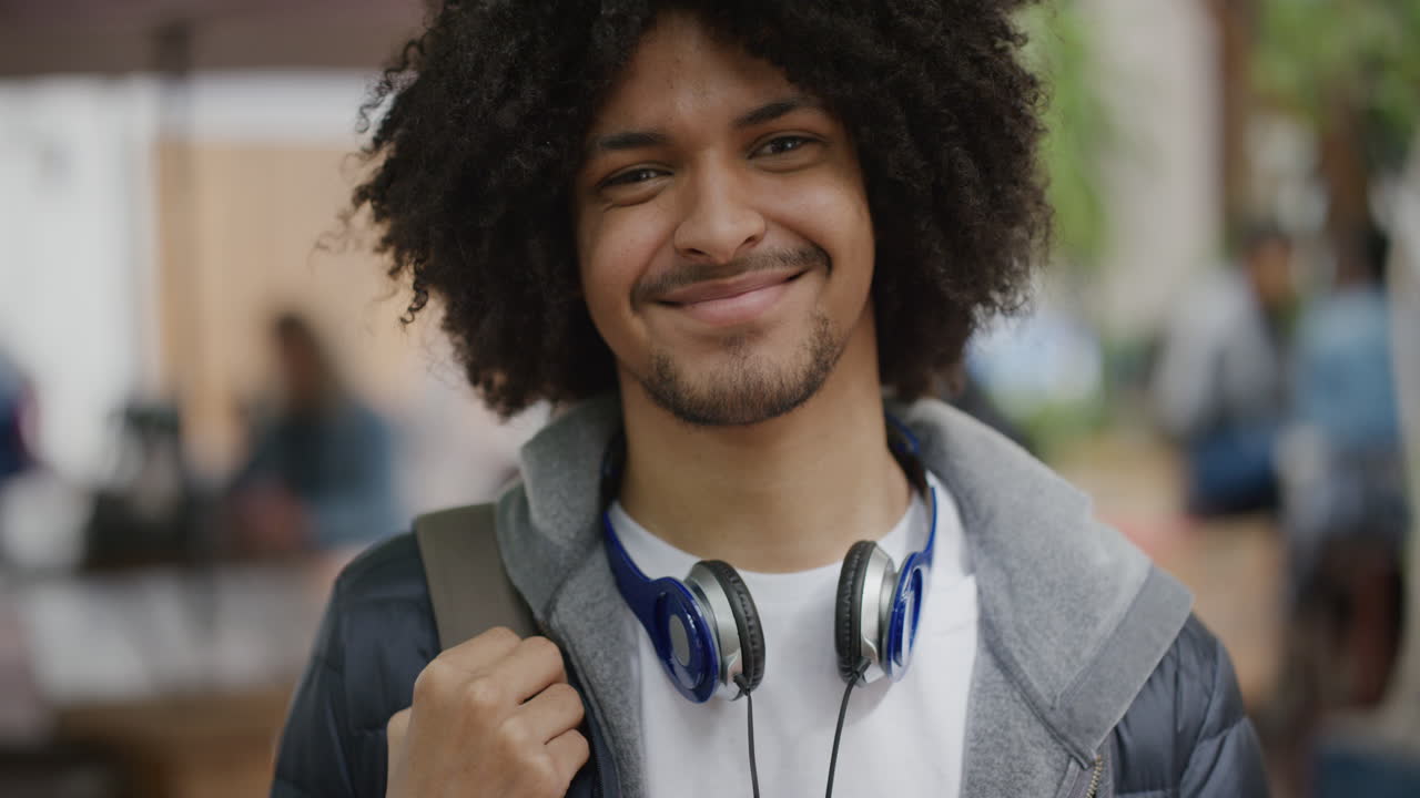 retrato de jovem confiante estudante de raça mista homem sorrindo feliz olhando para a câmera deslocando-se na cidade desfrutando do estilo de vida urbano estilo de cabelo afro legal