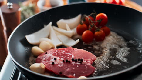 steak with tomatoes, garlic, and onions in a frying pan