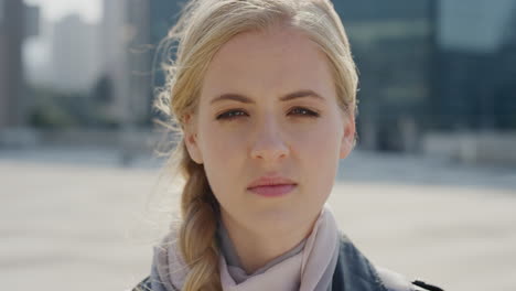 close up portrait beautiful blonde woman looking serious at camera in city wind blowing hair pensive caucasian female slow motion