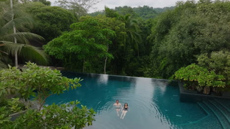 couple relaxing in an infinity pool surrounded by a lush jungle