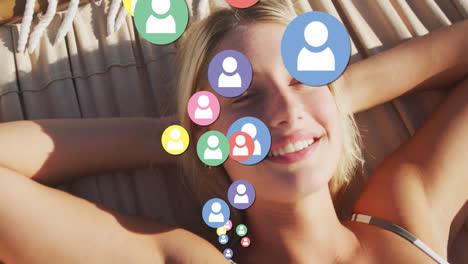 multiple profile icons floating against portrait of caucasian woman laying on hammock at the beach