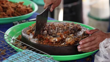 hands mixing ingredients in a large pan.