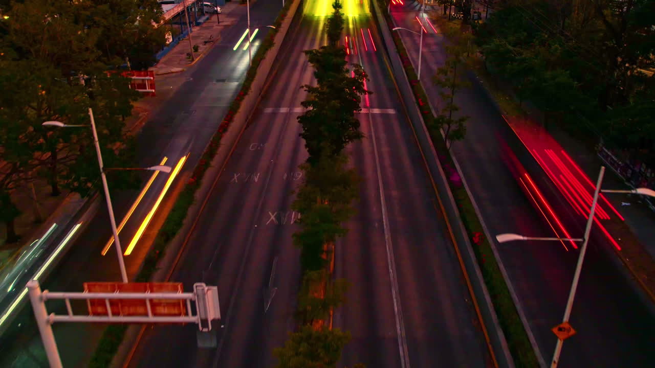 hiperlapso nocturno con el tráfico de vehículos en una bulliciosa avenida, con tonos amarillos y rojizos, evocando el ambiente de las ciudades mexicanas