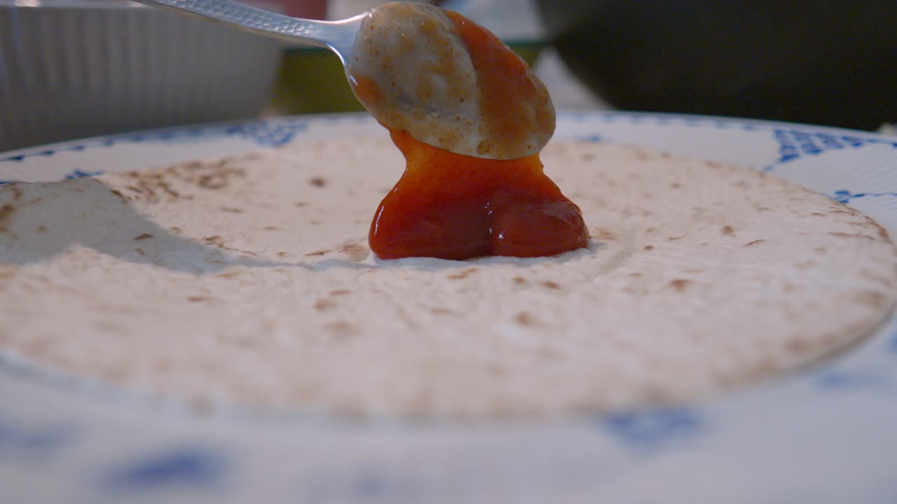Salsa Sauce Gently Placed by Spoon on Tortilla Wrap Ready for Spicy Mexican Fajitas Mix. Family Dinner Food Setting.