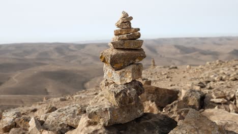 tight focus on a conical stone cairn while revealing endless barren countryside