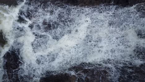 lateral camera movement with drone filming the descent of a beautiful waterfall very close, flowing waters