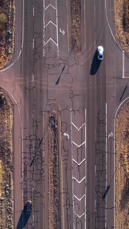 vertical drone shot, traffic on american desert road, state route with vehicles and cracked asphalt, birdseye view