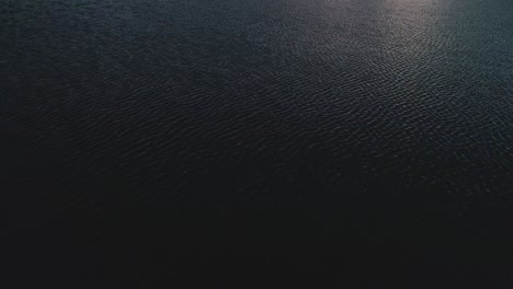 aerial view of sunlight sparkle on dark water surface - background