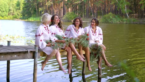 pretty women in ethnic dresses with floral circlets sitting on wooden bridge