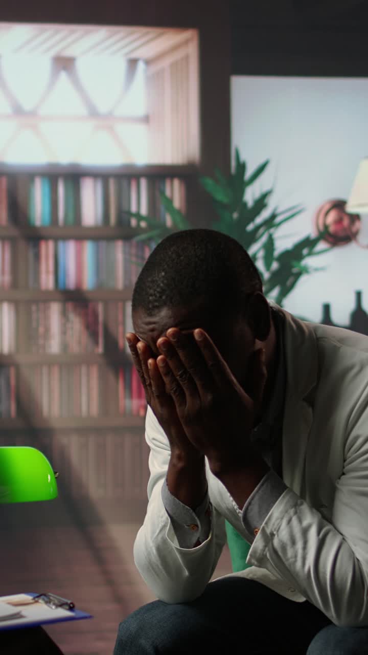 Uomo afroamericano angosciato che si copre il viso con le mani