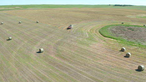 dramatic right to left panning shot of tractor harvesting hay bales