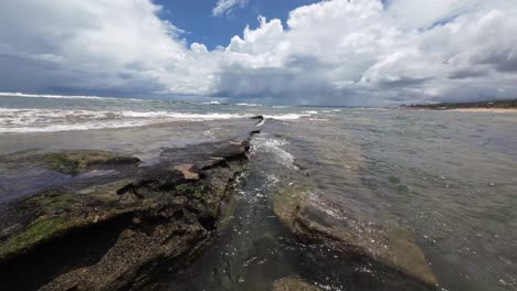 hermoso paisaje en cámara lenta de pequeñas olas que se estrellan sobre grandes rocas de la playa de tibau do sul cerca de pipa, brasil en río grande do norte durante un día nublado de verano