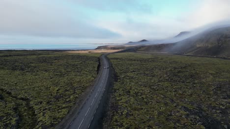 Drone-shot-of-car-driving-in-Iceland-during-winter-in-moss-field