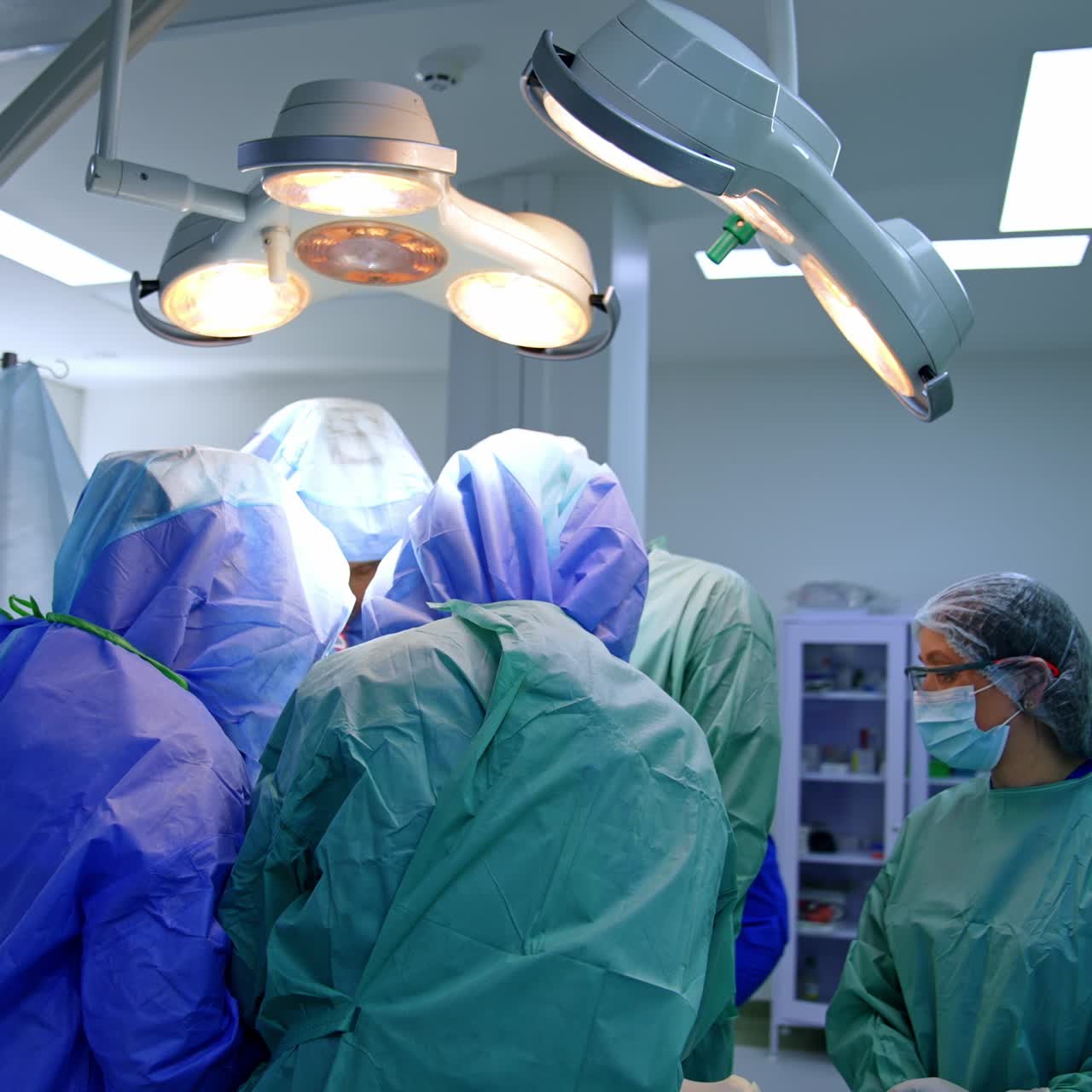 Surgeons wearing protective helmets surrounding the operational table. Doctoral team cooperating at trauma surgery