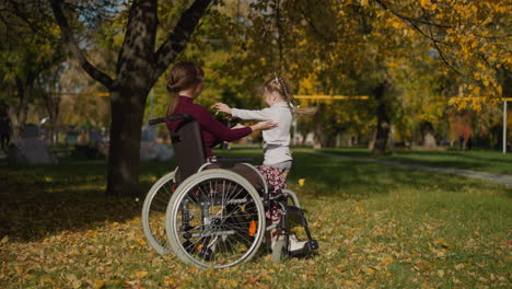 Young-mother-in-wheelchair-extends-hands-to-dancing-daughter