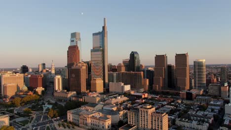 Cinematic-slow-aerial-reverse-turn-above-Benjamin-Franklin-Parkway-in-Philadelphia-at-golden-hour-during-summer-evening