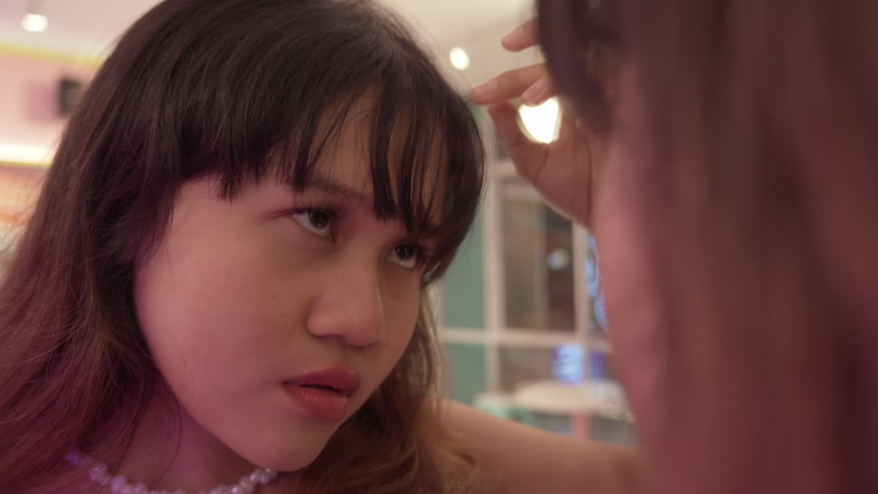 A woman inspects her bangs in a mirror with focus and curiosity indoors, close-up