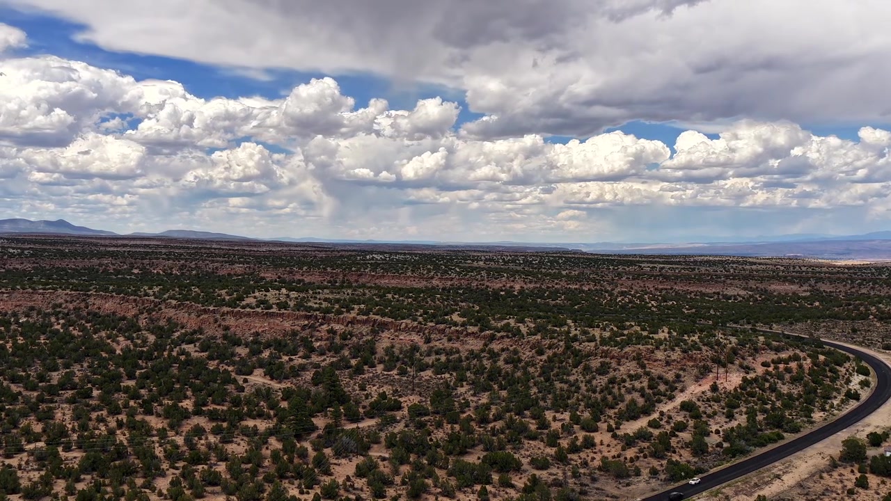 4K drone-tidsforløb af et dynamisk klima og hurtigt bevægende skyformationer. Et skiftende vejrsystem kaster lange skygger hen over en stor ørkenmesa og motorvejstrafik, der kører ind i White Rock, New Mexico