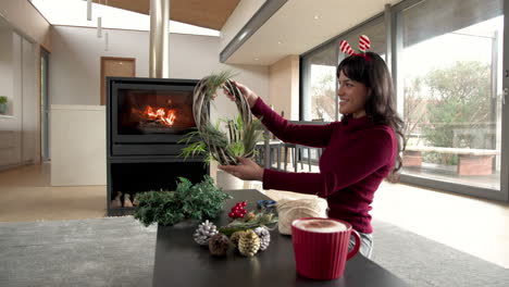 woman crafting christmas wreath at home, enjoying festive holiday decorations