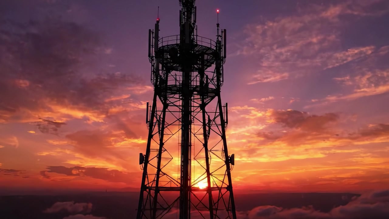 Una Transizione Mozzafiato: La Silhouette di una Torre Sotto un Cielo Vibrante al Tramonto Illuminato da Colori Caldi e Nuvole in un'Atmosfera Serale Magica