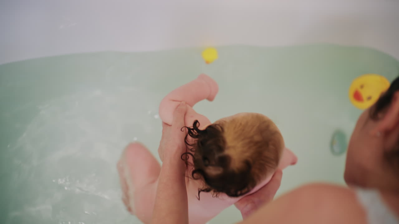 Close up of baby watching rubber duck toy during bath time