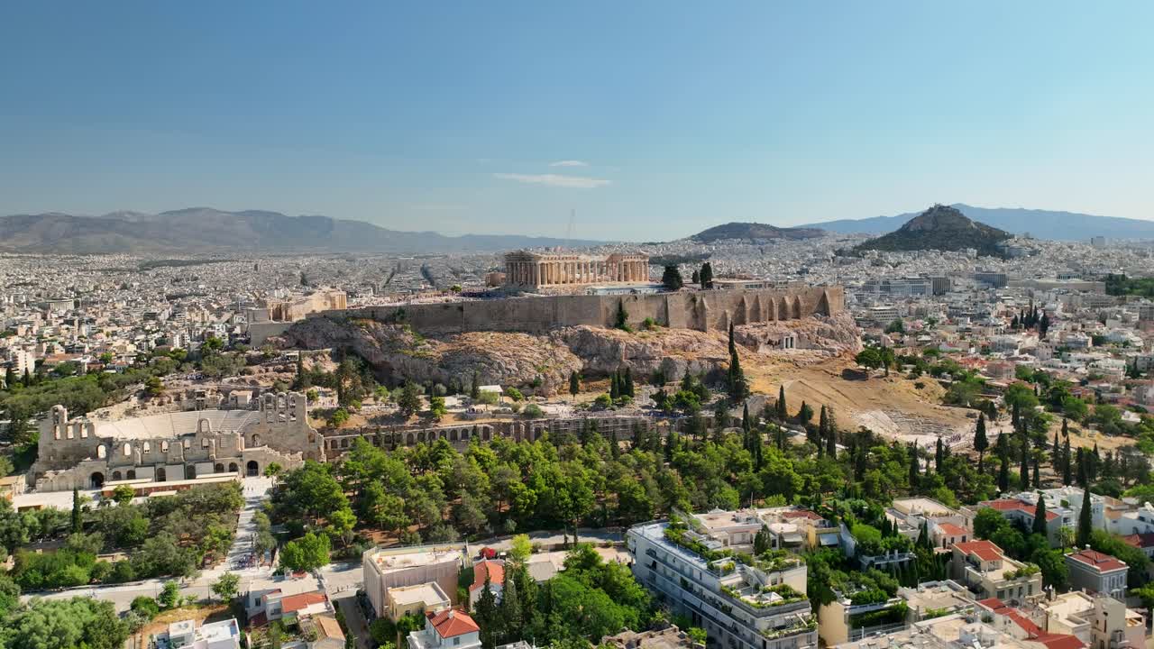 Aerial UHD footage of Acropolis, shot in full daylight, showing ancient columns, theater, and classical architecture with sprawling Athens in the background.