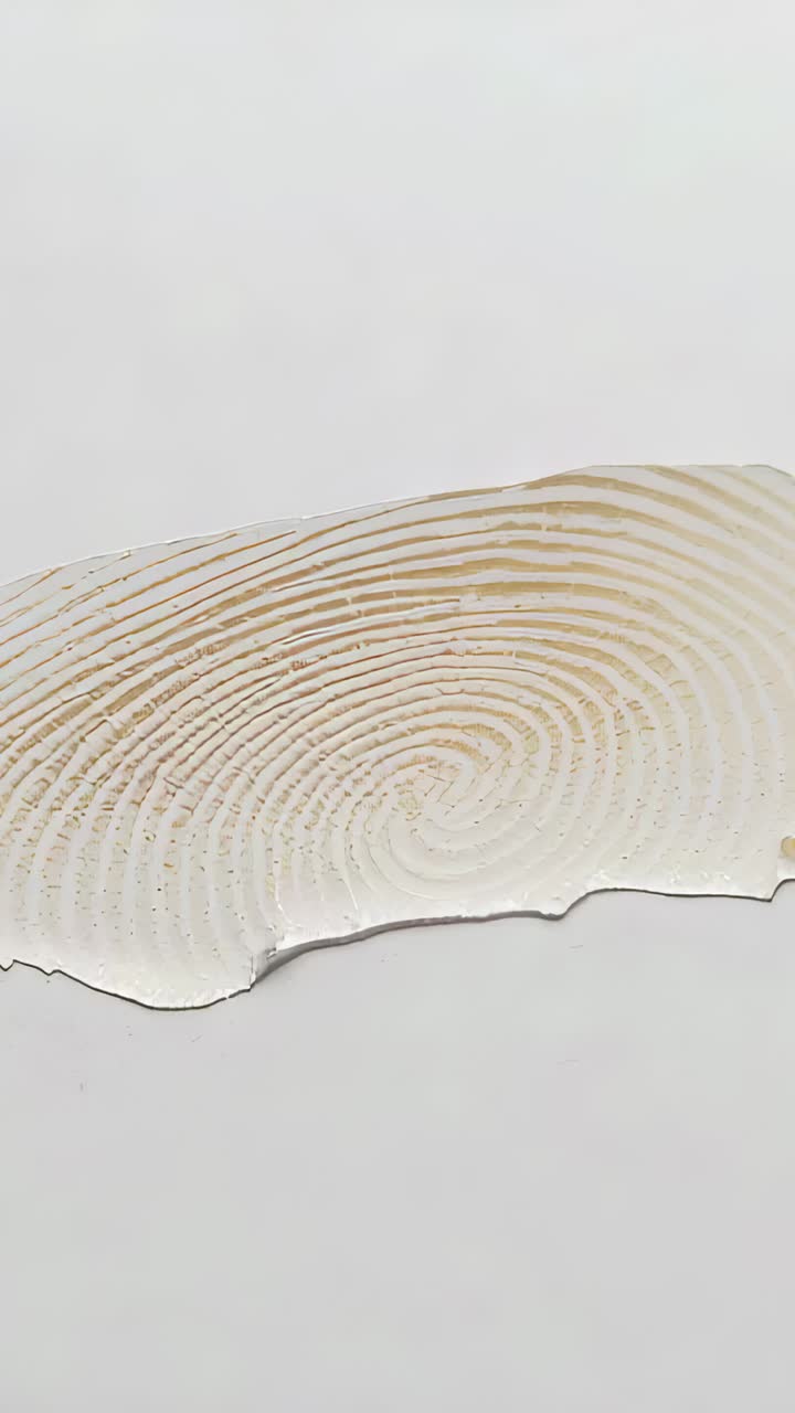 Vertical video: Filming camera making shifts while documenting thin strip's spiral ridges in studio