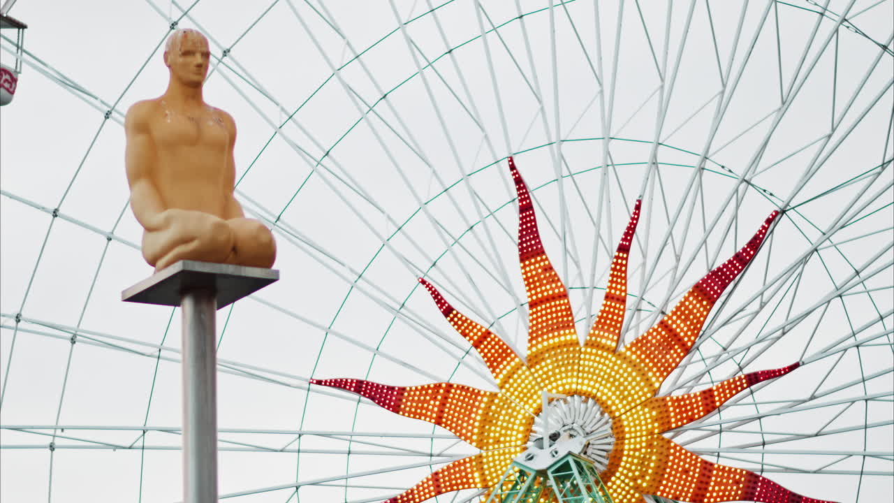 Nice, France - December 8, 2024: Conversation a Nice statue by Jaume Plensa at Place Massena with a ferris wheel on the background
