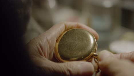 elderly person examines gold pocket watch