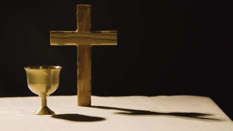 religious concept shot with wooden cross and chalice on altar in pool of light 1