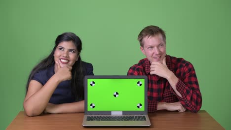 joven pareja de negocios multiétnica juntos contra un fondo verde