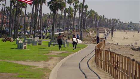 Surfer-Mit-Surfbrettern-Auf-Dem-Radweg-In-Huntington-Beach,-Kalifornien