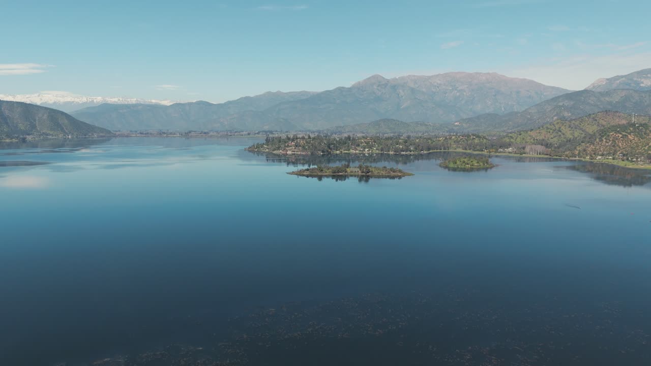 vista aérea de la laguna de aculeo que refleja las montañas andinas en un día soleado y despejado