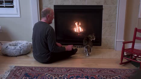 old senior man sitting by a fireplace with his cat