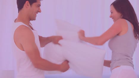 Pow-text-over-speech-bubble-against-caucasian-couple-playing-pillow-fight