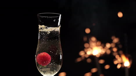 champagne flute and strawberry splashing with sparklers fireworks