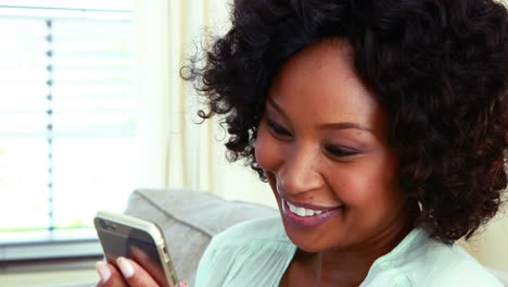 Woman-using-mobile-phone-on-sofa-in-living-room-4k