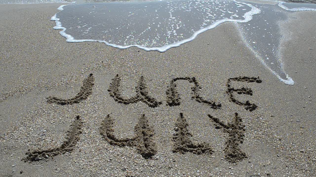Inscription of the name of month on sand, the beach. Shooting on the beach